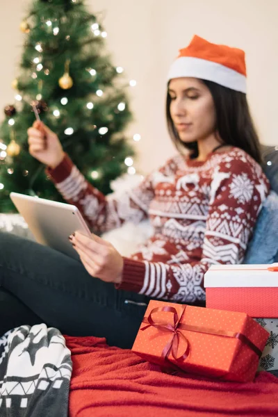 Mulher com chapéu de Santa à procura de presentes no tablet — Fotografia de Stock