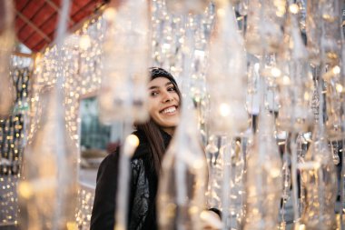 Bulanık ışık çelenklerinin arkasında duran mutlu kadın