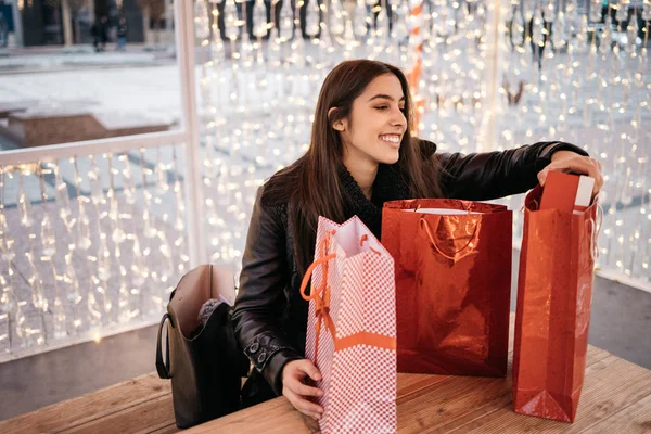 Улыбающаяся девушка достает подарок из подарочной сумки — стоковое фото