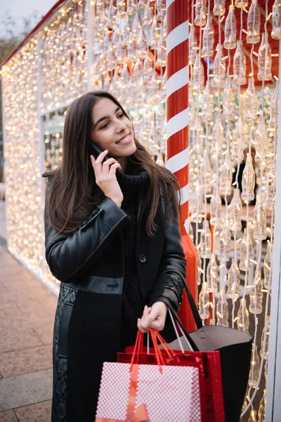 Glad flicka håller väskor och talar i telefon — Stockfoto