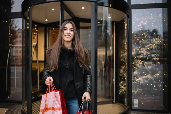 Smiling girl getting out from shopping mall
