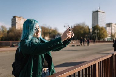 Köprüde dururken selfie çeken bir kadın.
