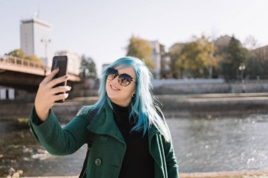 Nehrin kenarında duran bir kadın selfie çekiyor.