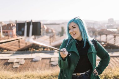 Kadın turist şehir manzarasının önünde duruyor ve selfie çekiyor.