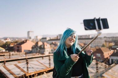 Mutlu kız selfie çekerken saçına dokunuyor.