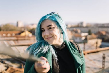 Gülümseyen kız selfie çubuğu tutuyor ve kameraya bakıyor.