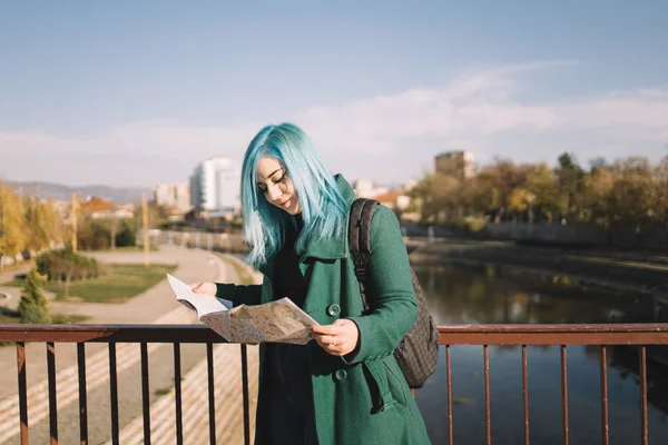 Girl wearing green coat searching for direction on map