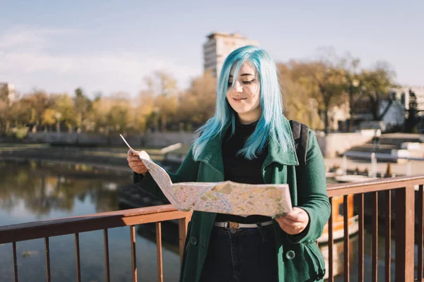 Sonriente chica sosteniendo abierto mapa en el puente — Foto de Stock