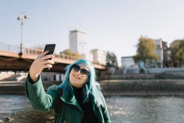 Podróżująca kobieta patrzy na telefon i robi selfie — Zdjęcie stockowe