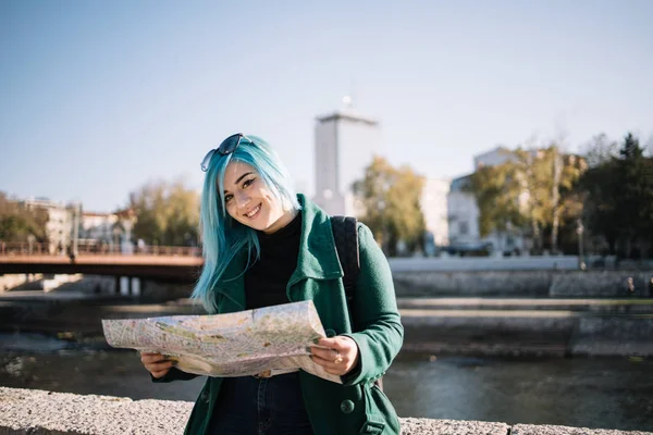 旅行の女の子地図と石のフェンスにもたれてカメラを見て — ストック写真