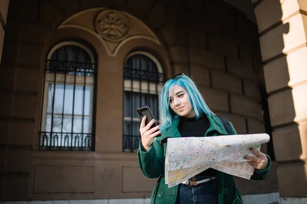 Tourist woman looking at phone and holding a map