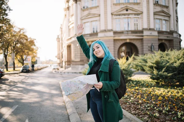 Turista femenina saludando mientras mira en un mapa — Foto de Stock