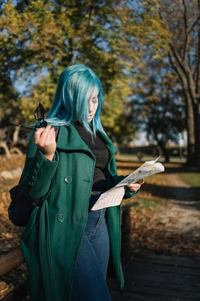 Pretty travel girl touching her blue hair in park