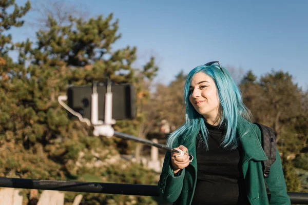 Милая девушка с голубыми волосами делает селфи в городском саду — стоковое фото