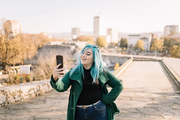Mujer joven mirando su teléfono con vista a la ciudad —  Fotos de Stock