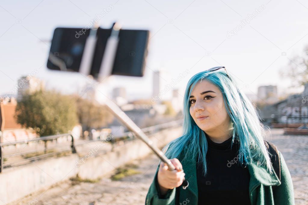 Young woman with blue hair taking selfie