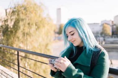 Mavi saçlı kız fotoğraf makinelerini kontrol ediyor.