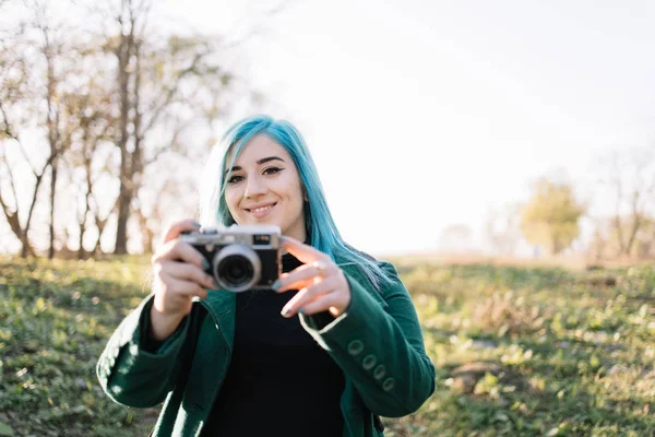 Menina olhando para uma câmera enquanto segurando câmera de fotos — Fotografia de Stock