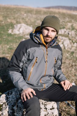 Sahadaki kayalıklarda oturan turistin yakın çekimi.