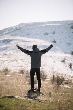Adamın arkası kar dağının önünde duruyor, elleri havada.