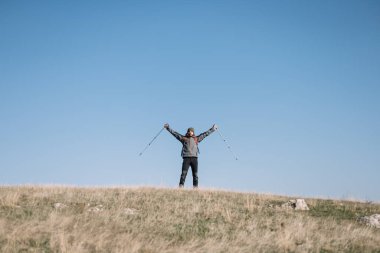 Gezgin adam ellerini tepenin üstüne koyuyor.