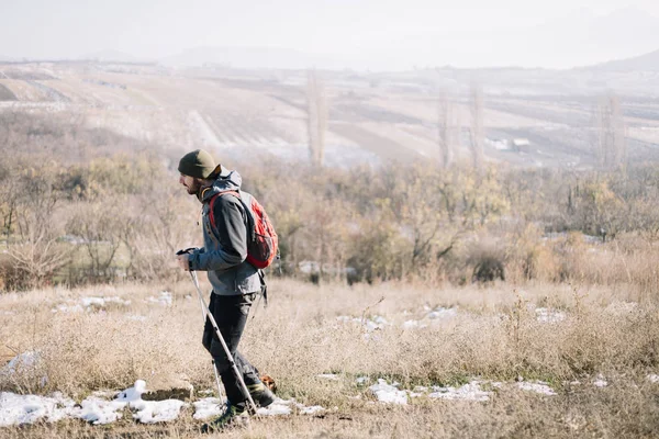 Toeristische man wandelen op het veld met uitzicht op de bergen — Stockfoto