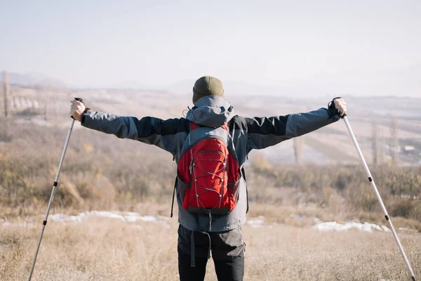 Parte de trás do homem usando mochila e postes de caminhada — Fotografia de Stock