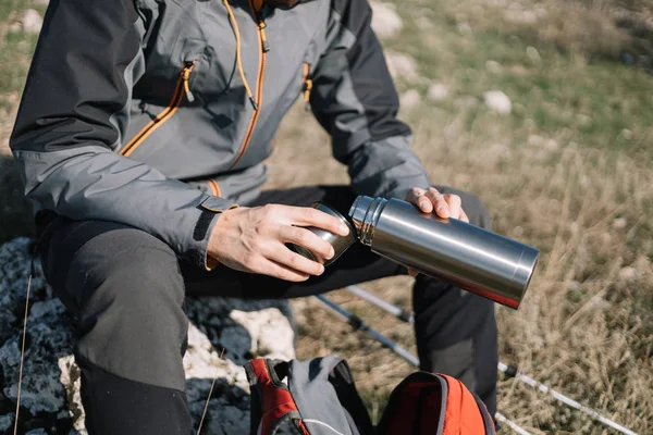 Mans handen houden thermoskan en gieten thee — Stockfoto