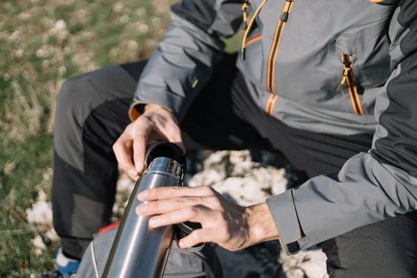 Hoge hoek uitzicht van wandelaar man gieten koffie uit thermoskan — Stockfoto