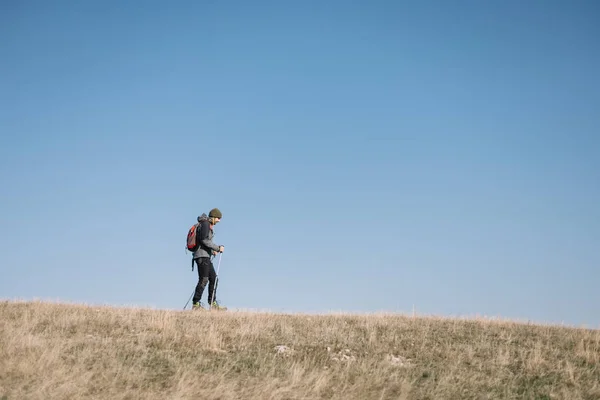 Young man walking on a hill with blue heavens