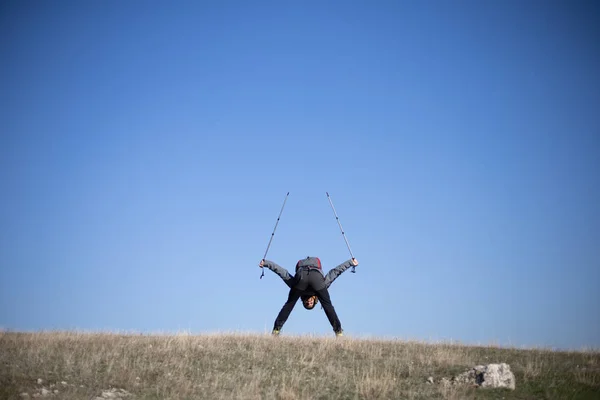 Hiker bends over and holding hiking poles in the air — 스톡 사진