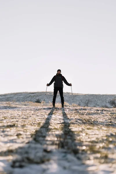 Uomo in piedi davanti a un sole e che tiene i pali — Foto Stock