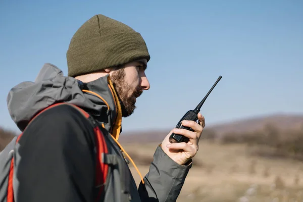 Tourist man speaking on mountain walkie talkie