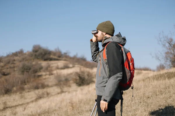 Hiker man standing on hill and using binoculars — 스톡 사진