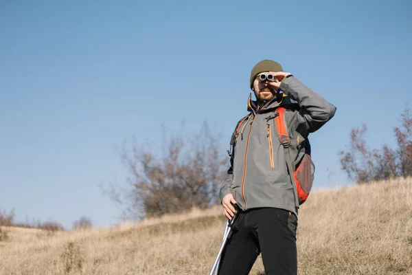 Hombre activo mirando a través de binoculares mientras está de pie en la colina —  Fotos de Stock