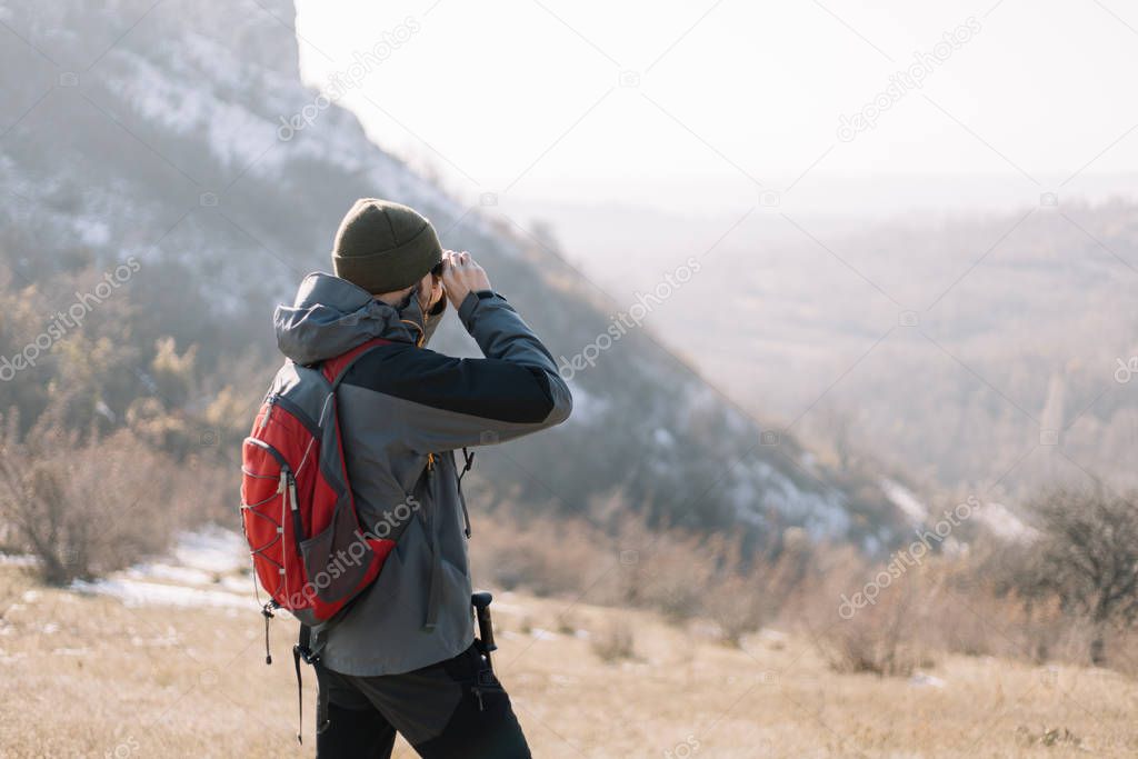 Back of a hiker man looking with binoculars