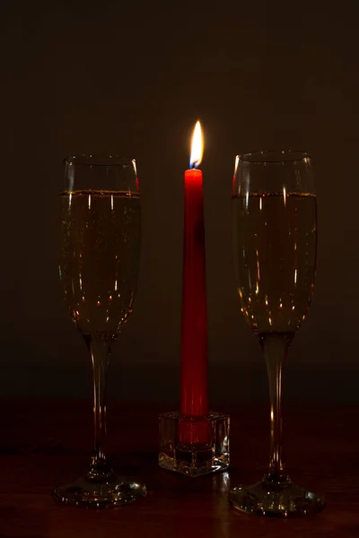 Burning red candle and two champagne glasses