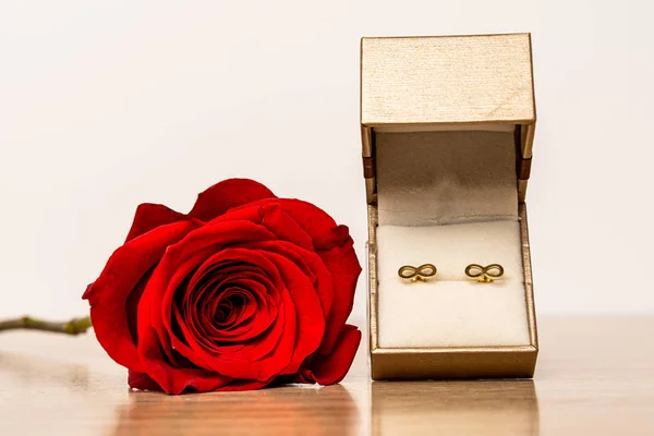 Gift box with golden earrings and red rose