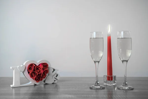 Wooden love frame, burning candles and champagne glasses