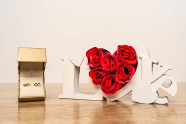 Hediye kutusunda küpeler ve güllü aşk işareti.