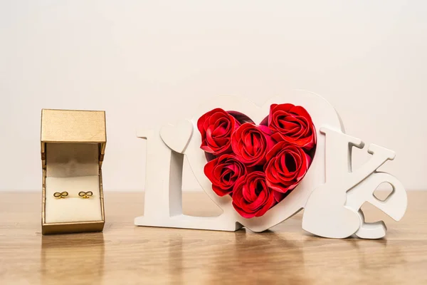 Earrings in gift box and love sign with roses