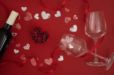 Kalp şeklinde bir kutu gül ve kırmızı şarap şişesi.