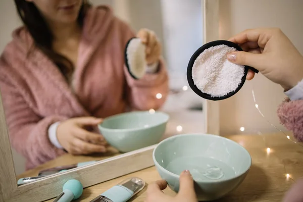 Mirrored image of woman holding cotton pad above a bowl — Stock Photo, Image
