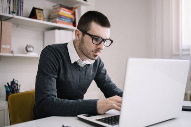 Ofiste dizüstü bilgisayarla çalışan sakallı genç iş adamı.