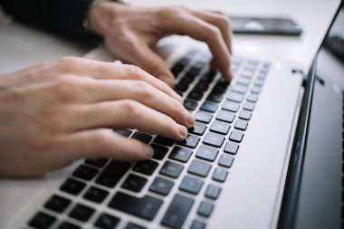 Dizüstü bilgisayarın klavyesinin üzerindeki ellerin yakın görüntüsü