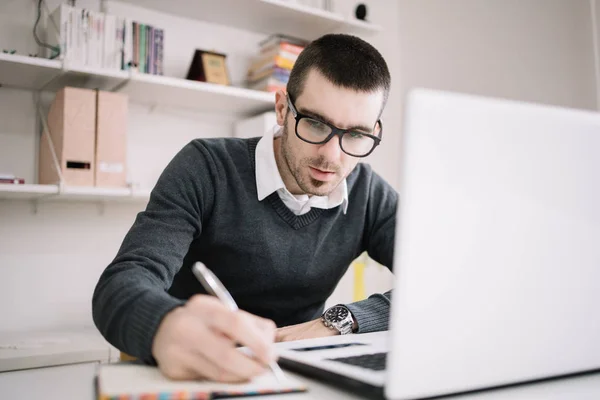 Young focused employee writing documents on office desk