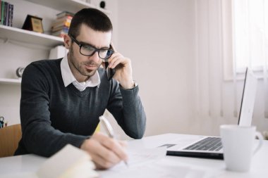 Evrak işleriyle uğraşan bir broker telefonda konuşuyor.