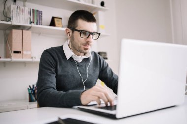 Ofis masasında dizüstü bilgisayarda çalışan erkek çalışan.