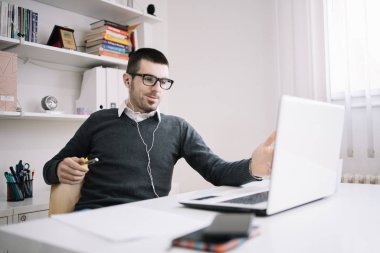 Gülümseyen adam masada otururken online toplantı yapıyor.