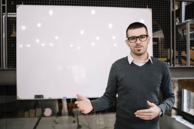 Genç işletme koçu beyaz tahtanın önünde duruyor.